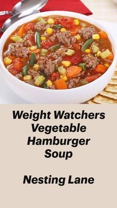 a white bowl filled with meat and vegetable soup next to crackers on a table