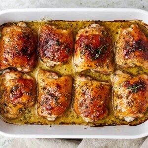 a casserole dish filled with meat covered in sauce and garnished with herbs