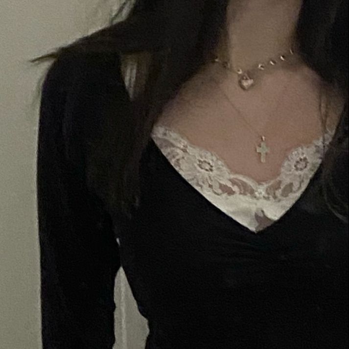 a woman with long hair wearing a black shirt and white lace collared top is standing in front of a door