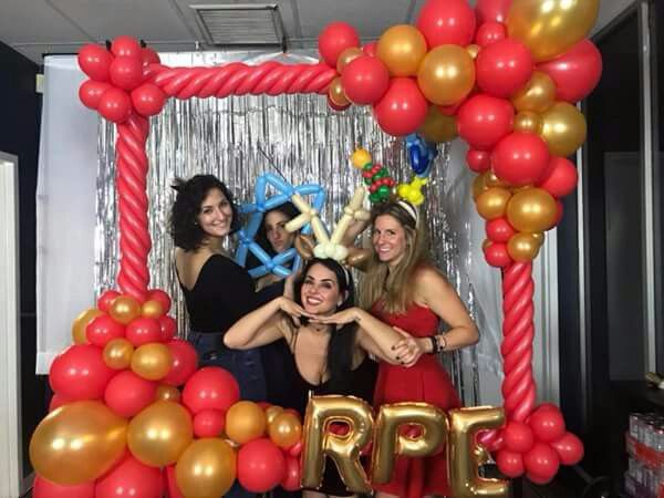 three women posing in front of a balloon arch with the word rrp on it