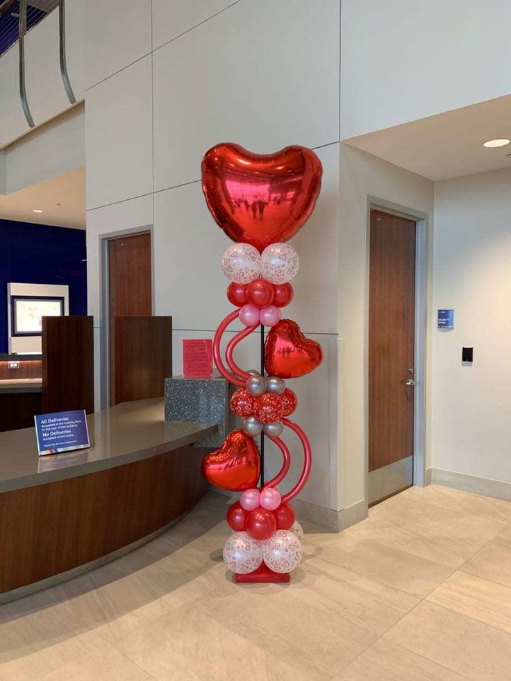 a large balloon sculpture in the shape of a heart is on display at an office lobby