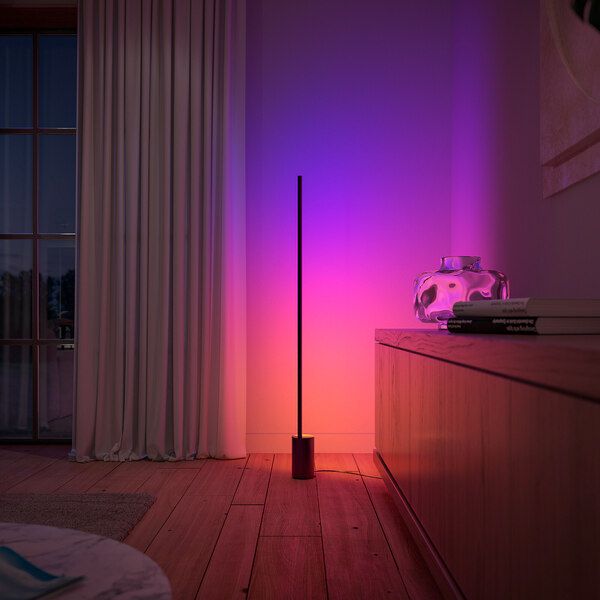 a pink and purple light shines on the wall next to a tall black pole