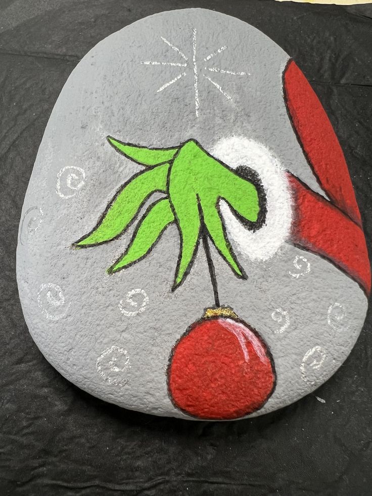 a painted rock with an image of a hand holding a cherries berry on it