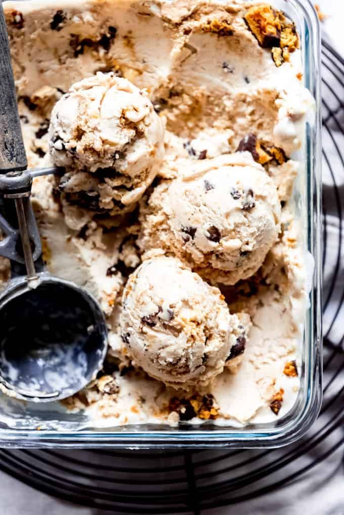 scoops of ice cream with chocolate chip cookies in a glass dish next to a spoon