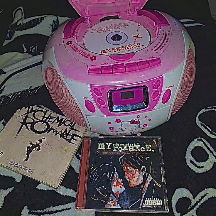 a pink cd player sitting on top of a bed next to a book and cds