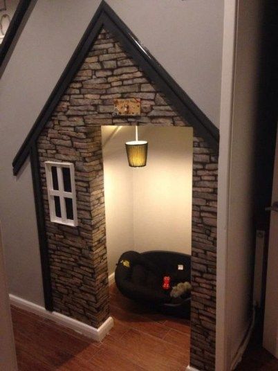 an indoor dog house made out of bricks and stone veneers, with a black couch in the doorway