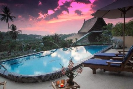 an outdoor swimming pool with lounge chairs and candles on the table next to it at sunset