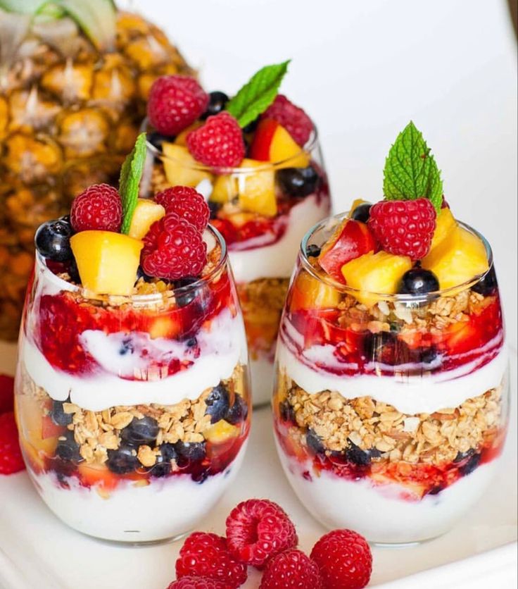 two glasses filled with fruit and yogurt on a plate