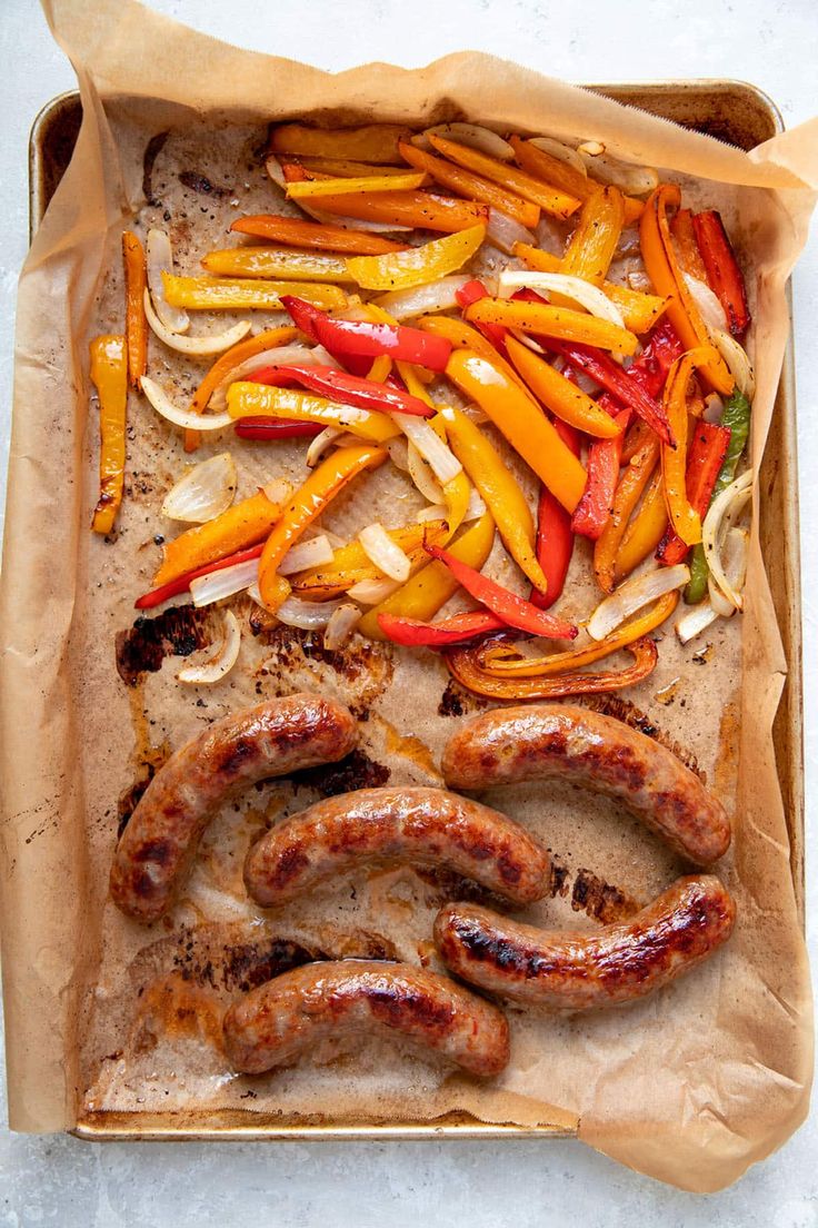 sausages, peppers and onions on a baking sheet with parchment paper in the middle