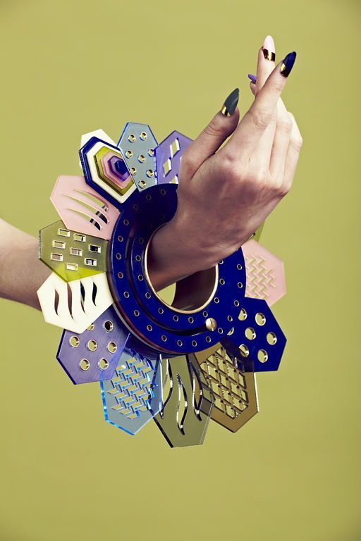 a woman's hand holding an object made out of paper and other items that are arranged in the shape of a circle