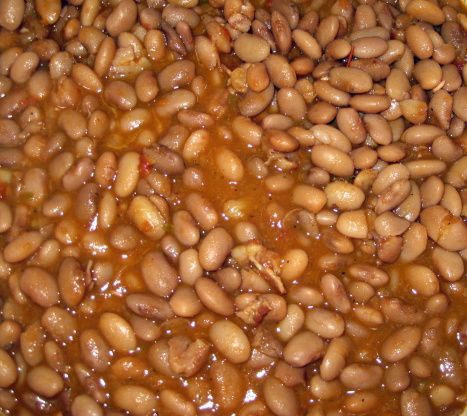 beans are being cooked in a pot with brown sauce on top and the bottom half