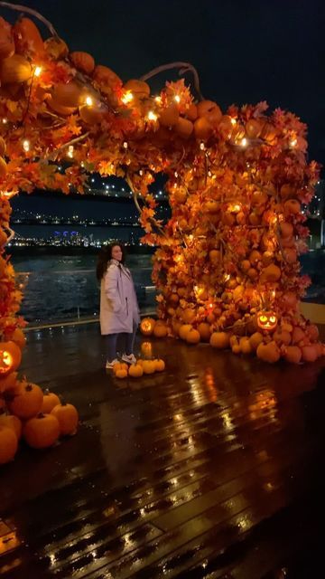 a woman standing in front of an archway decorated with pumpkins