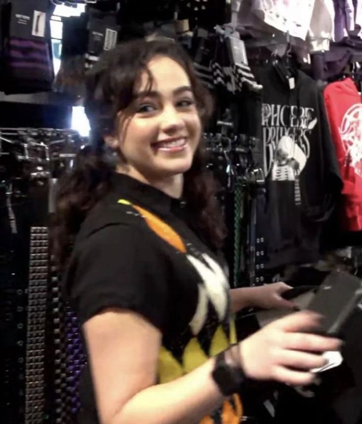 a woman standing in front of a rack of shirts