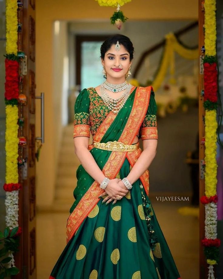 a woman in a green and gold lehenga is posing for the camera with her hands on her hips