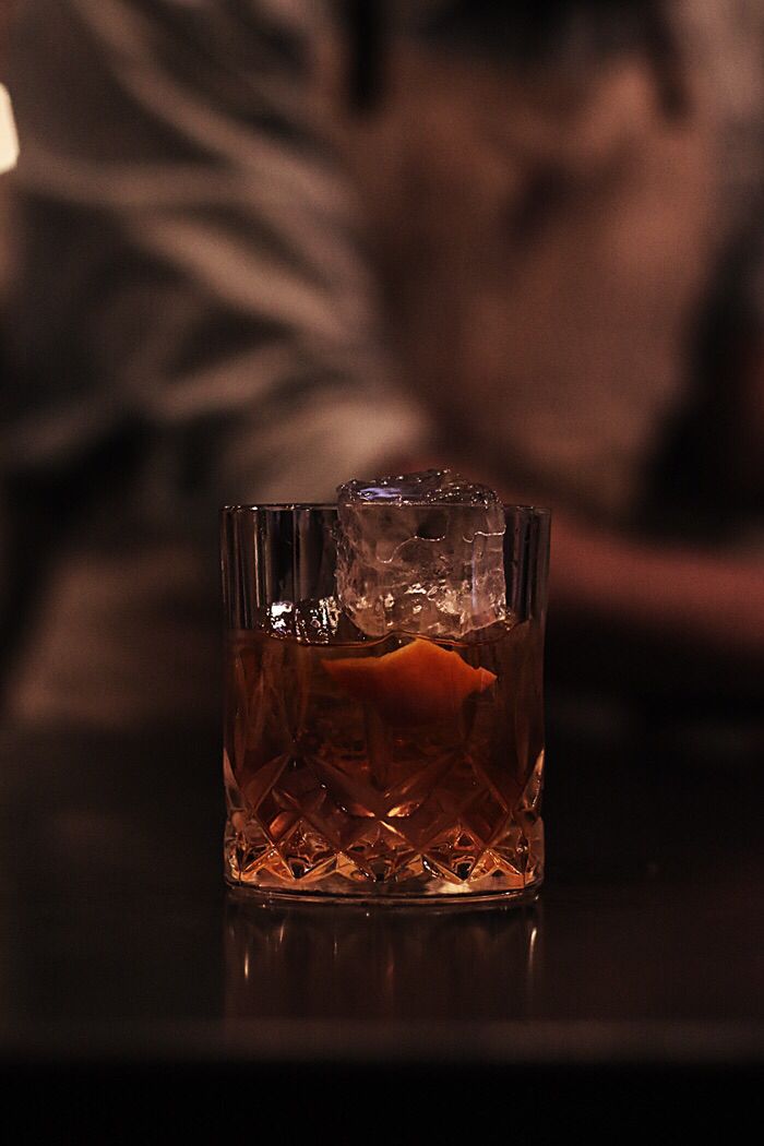 a glass filled with liquid sitting on top of a table next to a person laying down