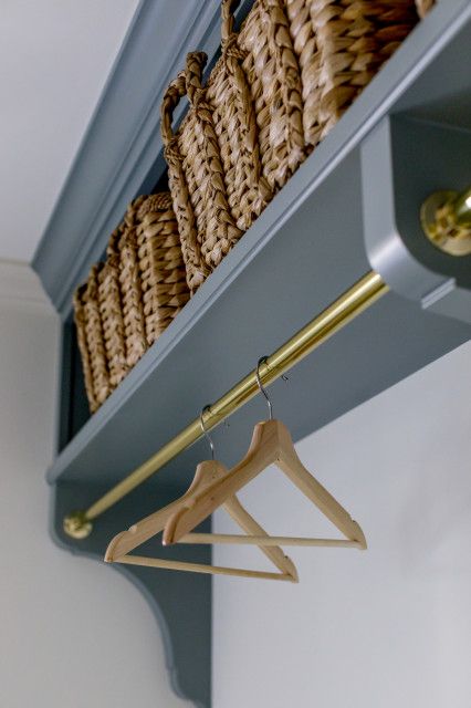 a shelf with baskets and clothes hangers on it