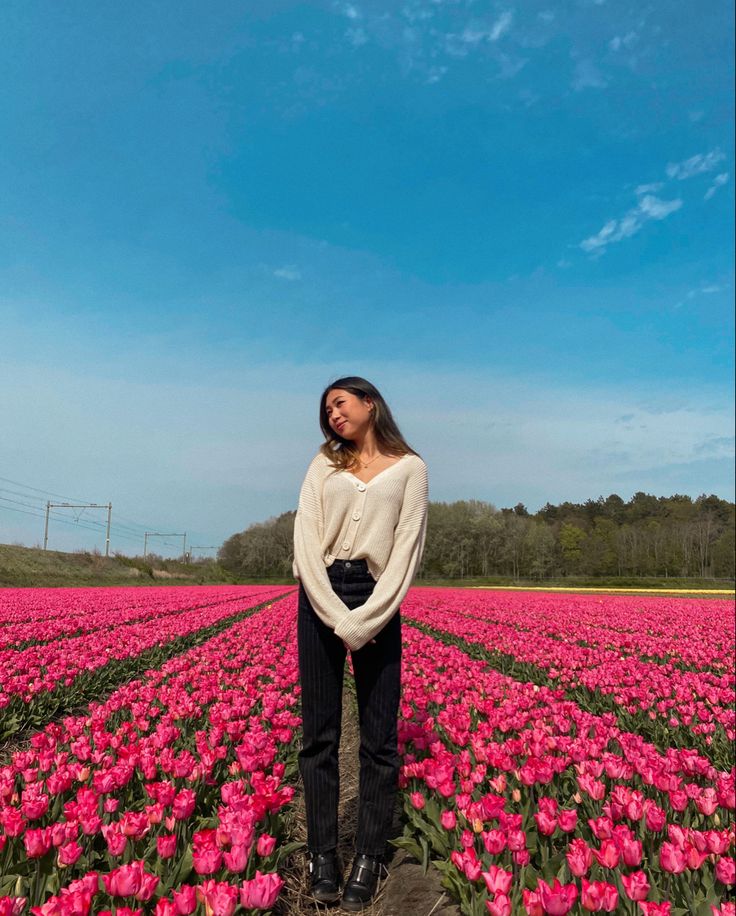 a woman standing in a field of pink tulips