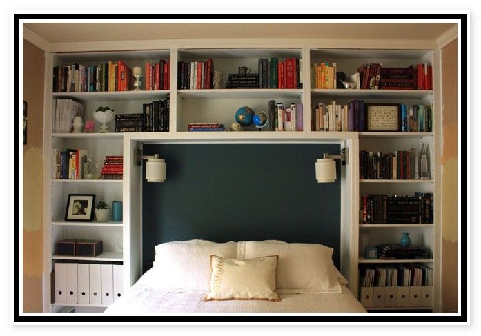 a white bed sitting in front of a book shelf filled with books