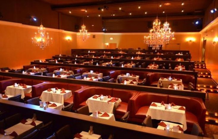 an empty restaurant with chandeliers hanging from the ceiling and tables covered in white tablecloths