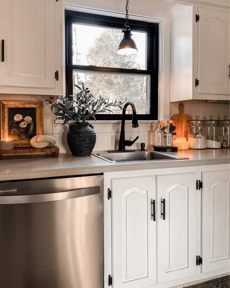 a kitchen with white cabinets and stainless steel dishwasher in the center, next to an open window