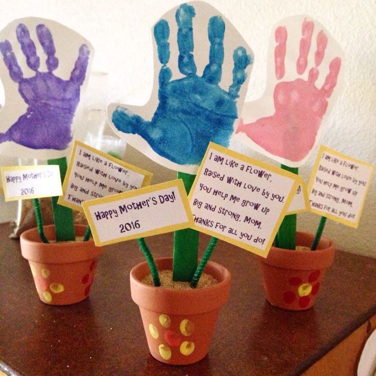 four handprints are placed in flower pots on a table with notes attached to them