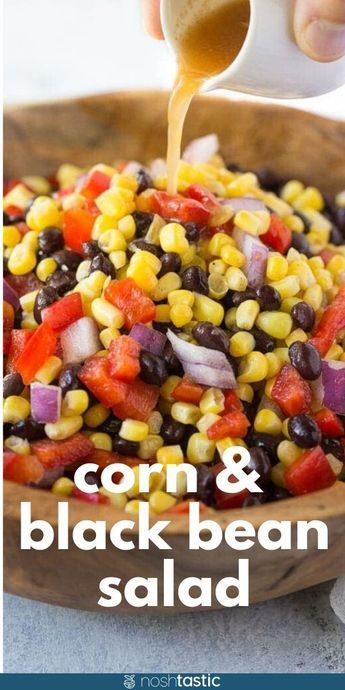 corn and black bean salad in a wooden bowl with a spoon being drizzled over it