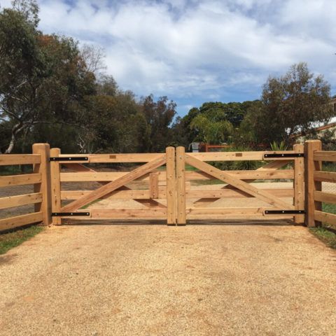 a wooden gate in the middle of a dirt road