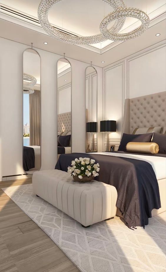 a bedroom with a large bed, mirror and chandelier on the wall above it