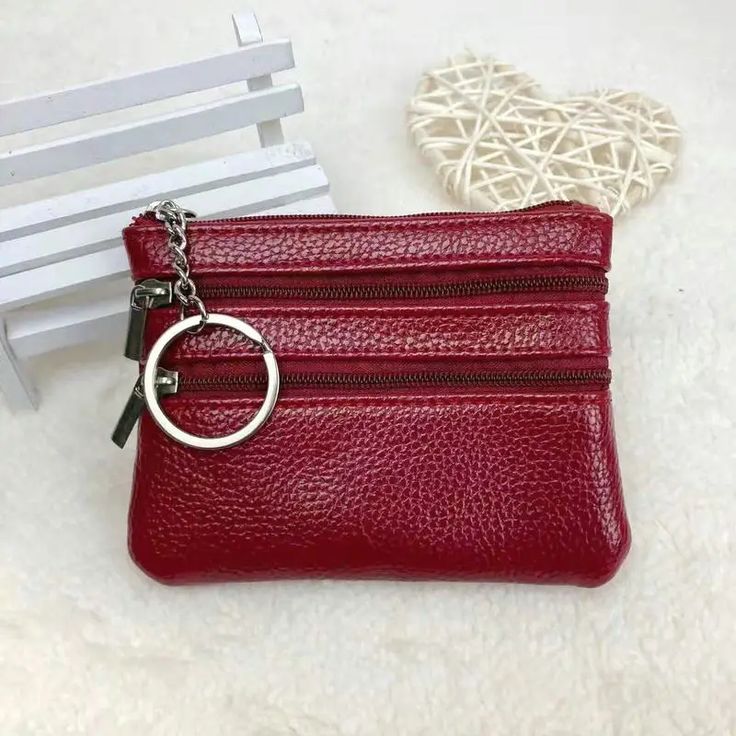 a small red purse with a metal ring on the front and zippered closures