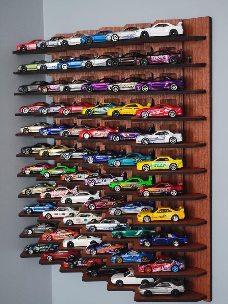 a wooden shelf filled with toy cars on top of a wall next to a gray wall