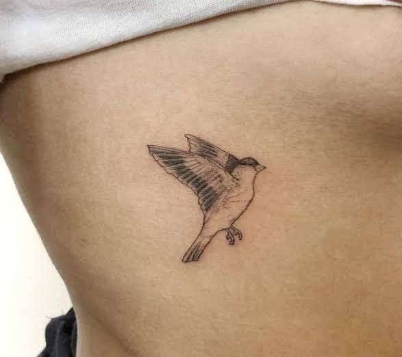 a small bird tattoo on the stomach