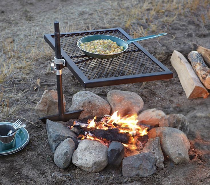 a fire pit with food cooking over it in the middle of some dirt and rocks