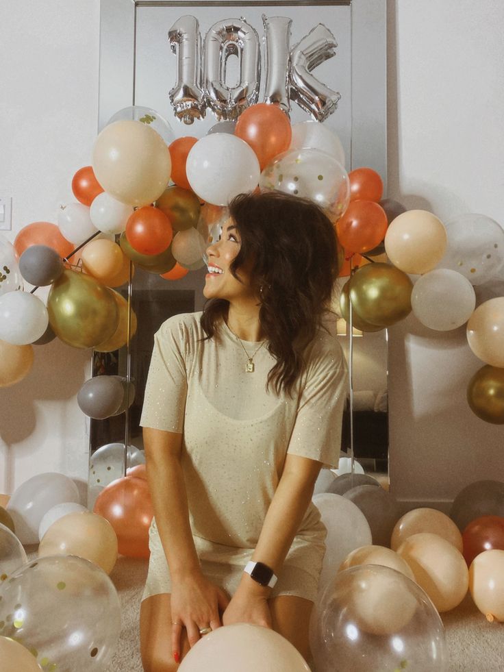 a woman sitting on the floor surrounded by balloons