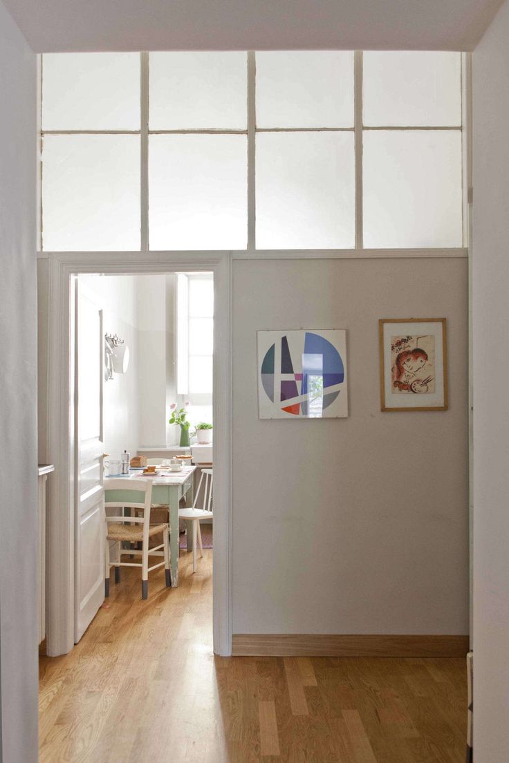 an open door leading to a dining room with wooden floors and white walls, along with pictures on the wall