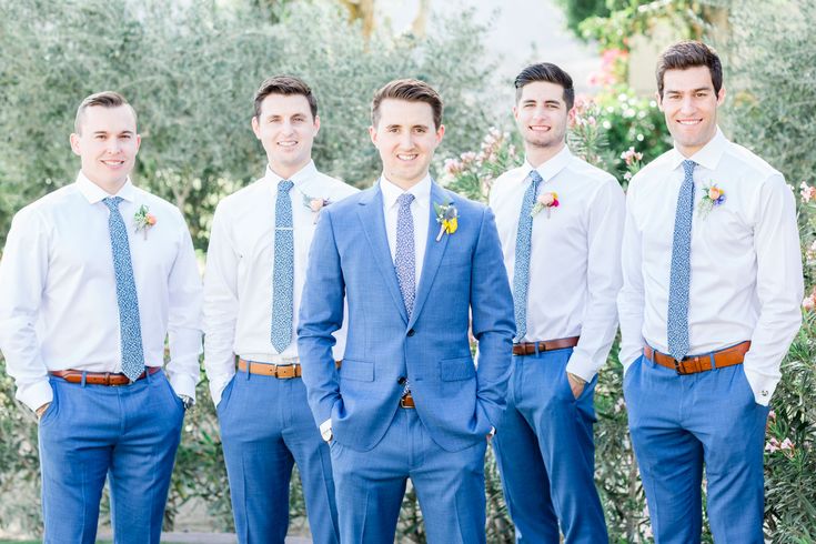 a group of men standing next to each other wearing blue ties and matching vests