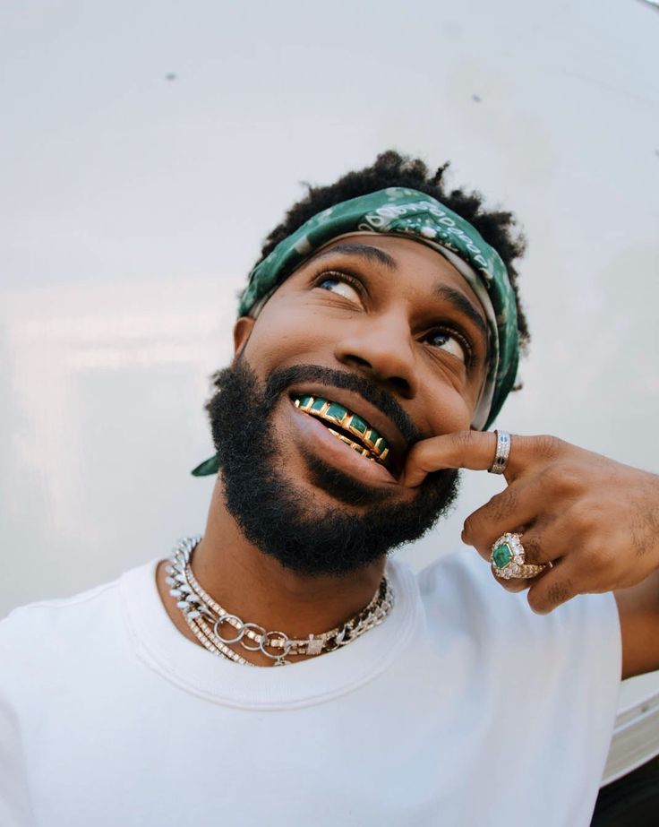 a man wearing a bandana and holding his finger up to his mouth with the other hand