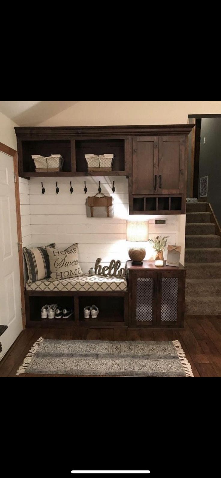 a living room with stairs and storage units on the wall next to a door that leads to a hallway