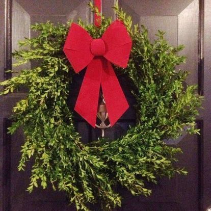 a wreath with a red bow hanging on the front door