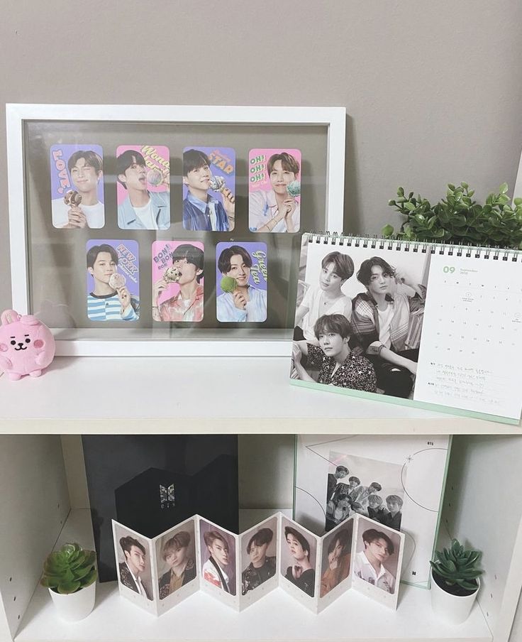 a shelf with pictures, photos and a pink teddy bear on it next to a calendar