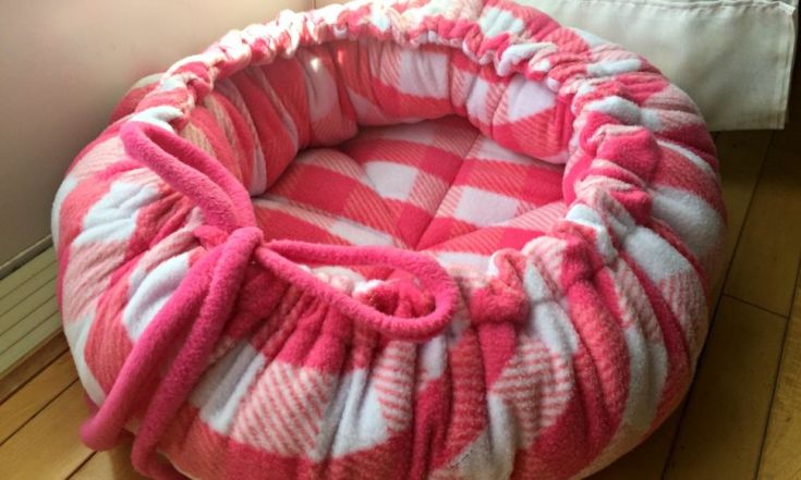 a pink and white pet bed on the floor