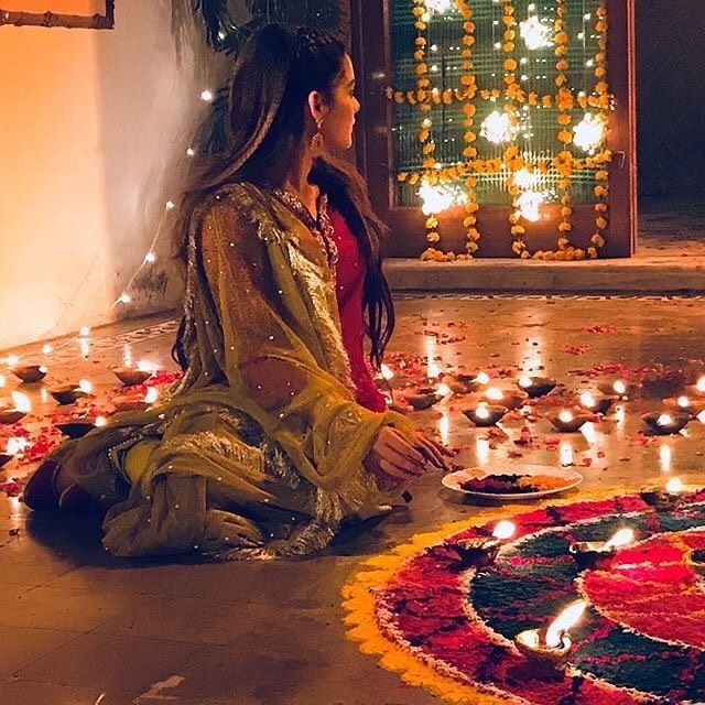 a woman sitting on the floor in front of a decorated circle with lit candles around her