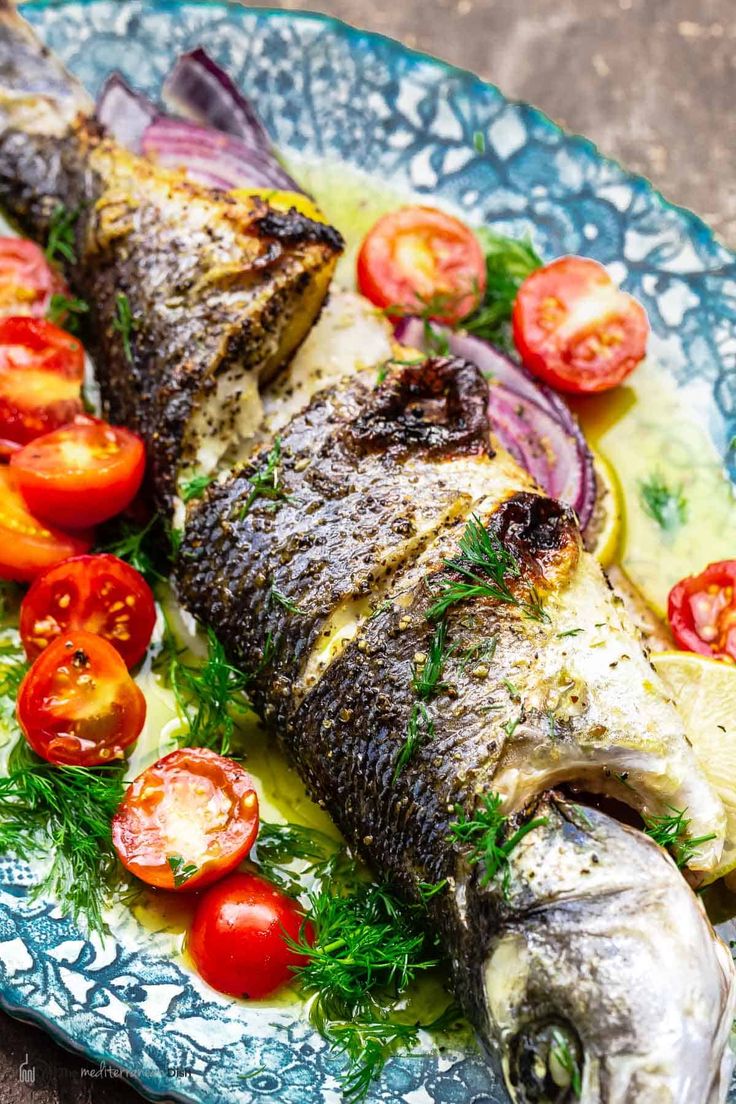 grilled whole fish on a plate with tomatoes and herbs