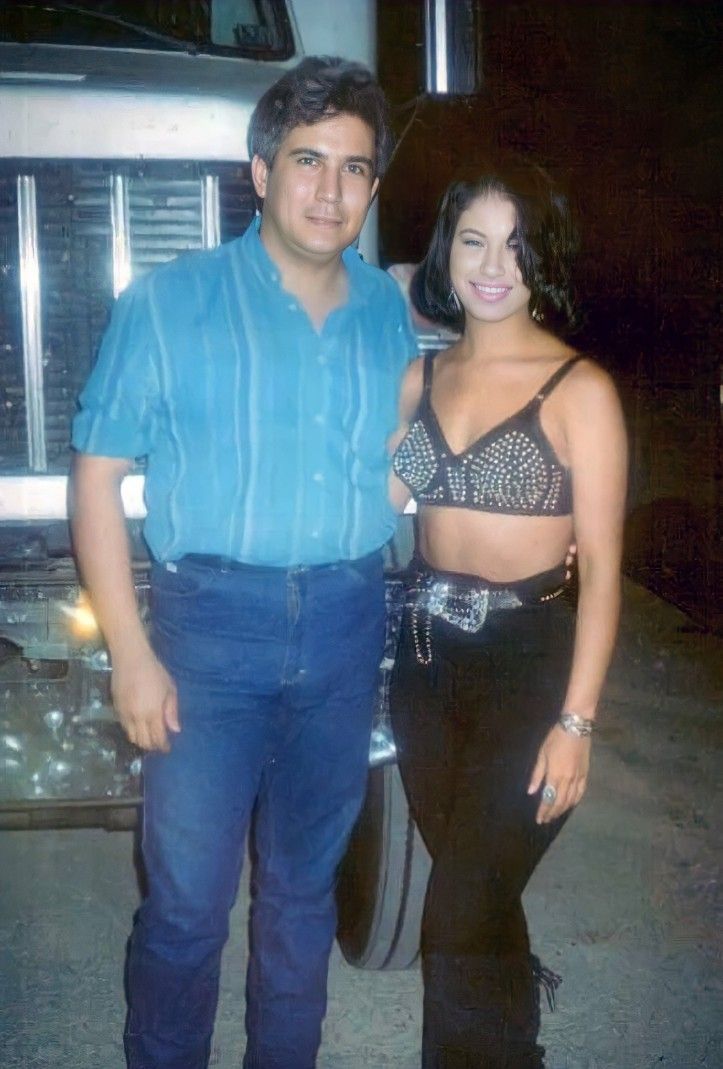 a man and woman standing next to each other in front of a truck at night