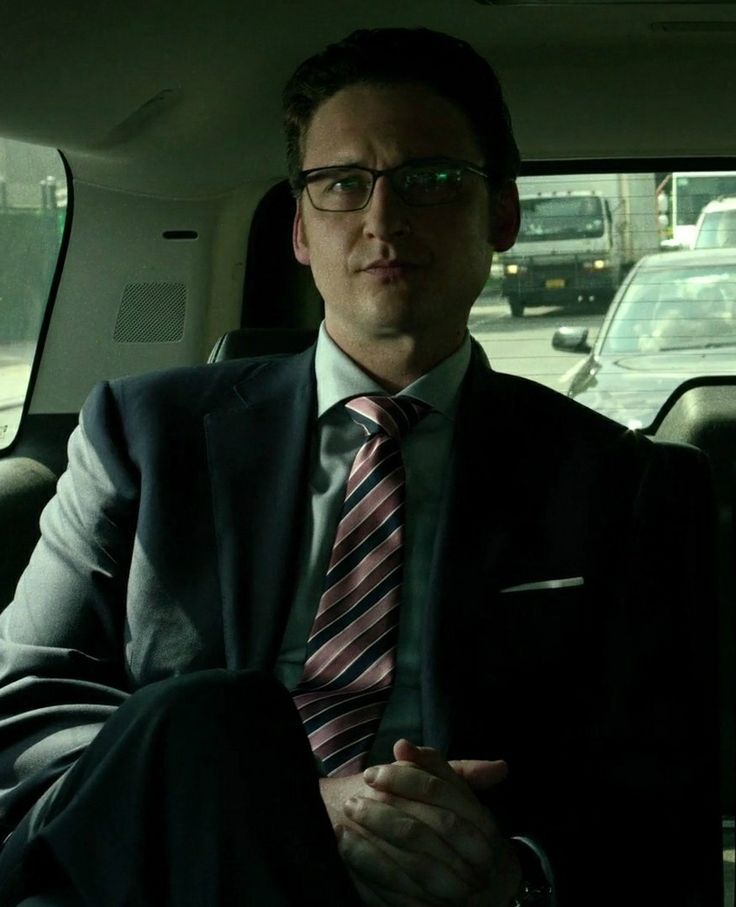 a man sitting in the back seat of a car wearing a suit and striped tie