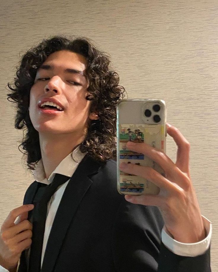 a man in a suit taking a selfie with his cell phone while wearing a tie