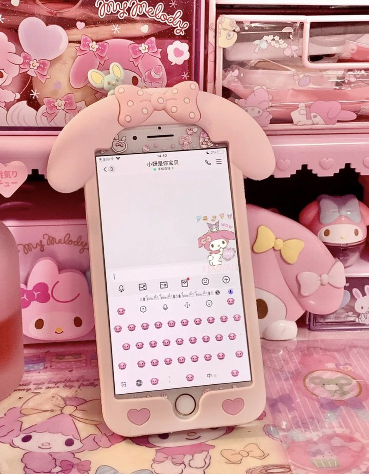 a cell phone sitting on top of a table next to some pink boxes with hello kitty decorations