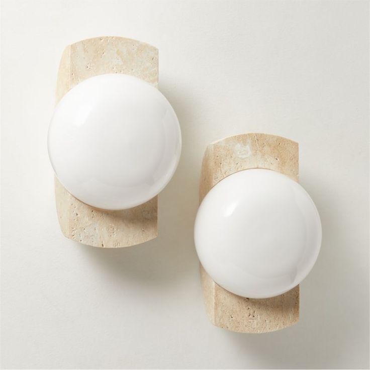 two white ceramic knobs on a wall