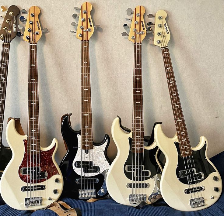 three electric guitars are lined up on a blue sheet and one is black, the other is white