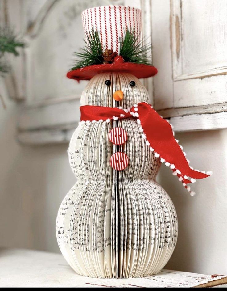 a snowman made out of book pages with a red hat and scarf on it