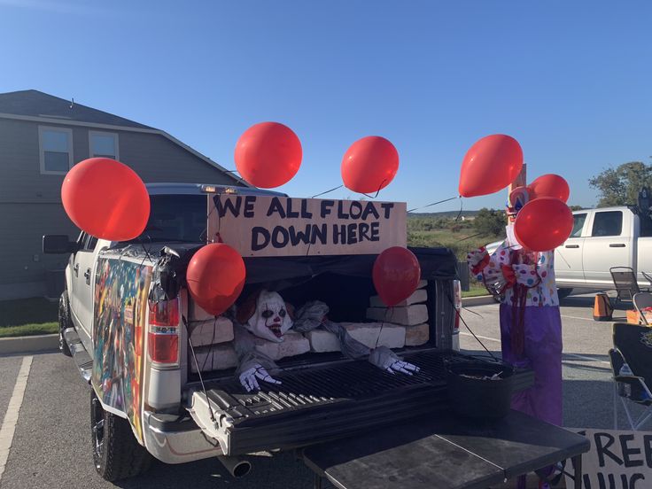 two clowns are sitting in the back of a truck with balloons attached to it